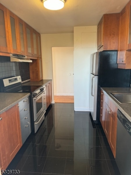 kitchen with backsplash, stainless steel appliances, dark tile patterned floors, and sink