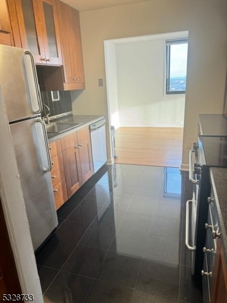 kitchen with dark tile patterned flooring, decorative backsplash, sink, and appliances with stainless steel finishes