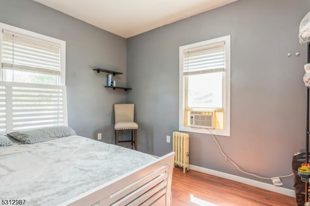 bedroom featuring cooling unit, radiator, and light hardwood / wood-style flooring