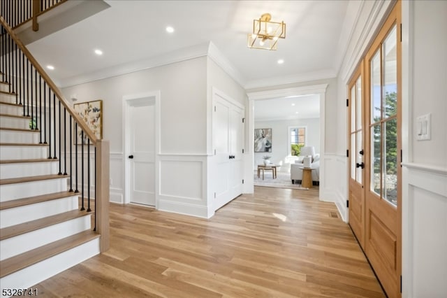 entrance foyer with a chandelier, light hardwood / wood-style flooring, and ornamental molding