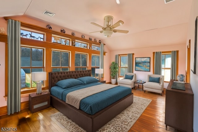 bedroom featuring multiple windows, lofted ceiling, and light wood-type flooring