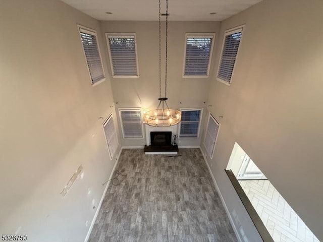 unfurnished living room featuring a healthy amount of sunlight, wood-type flooring, a high ceiling, and a chandelier