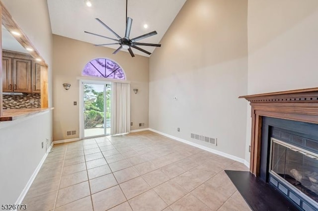 unfurnished living room with high vaulted ceiling, ceiling fan, and light tile patterned flooring