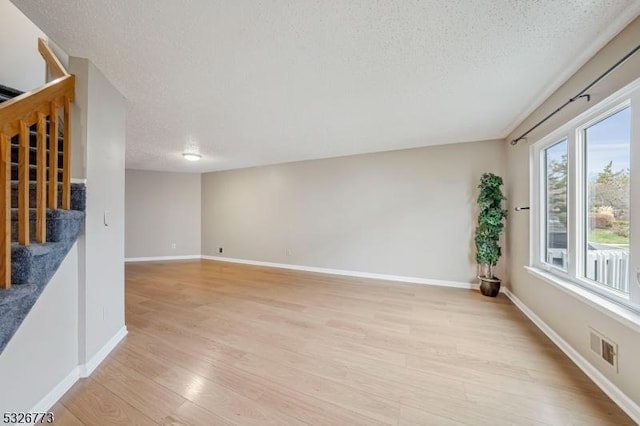 spare room featuring light hardwood / wood-style floors and a textured ceiling