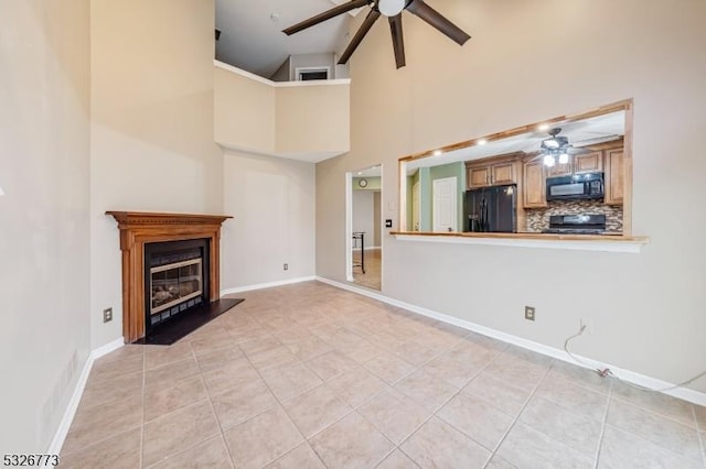 unfurnished living room with ceiling fan, light tile patterned flooring, and high vaulted ceiling