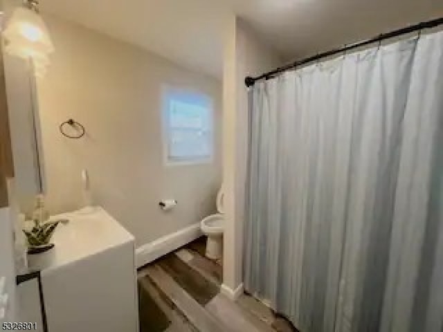 bathroom with hardwood / wood-style floors, vanity, toilet, and a shower with shower curtain