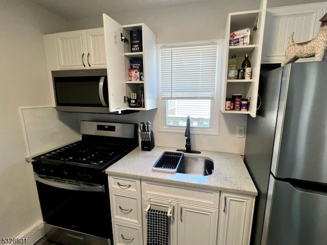 kitchen with backsplash, sink, light stone countertops, white cabinetry, and stainless steel appliances