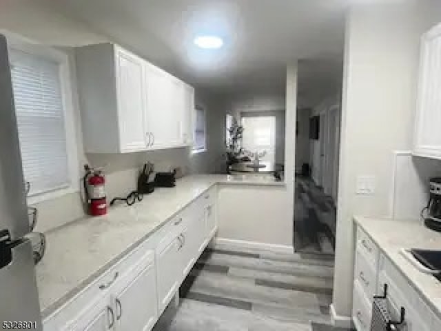 kitchen with white cabinets, light hardwood / wood-style floors, and light stone countertops