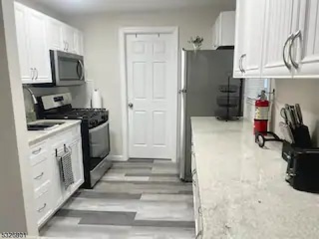 kitchen with white cabinets, light hardwood / wood-style floors, and appliances with stainless steel finishes