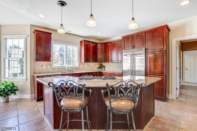 kitchen featuring decorative backsplash, a wealth of natural light, a kitchen island, and appliances with stainless steel finishes