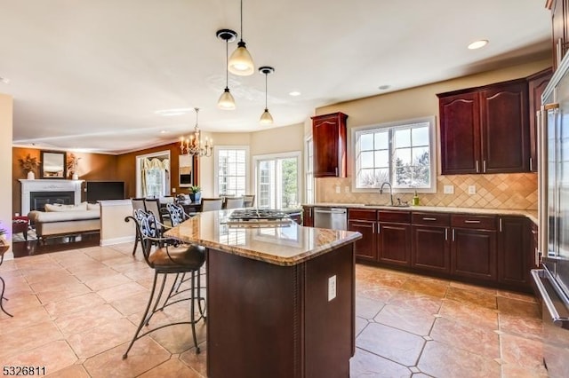 kitchen featuring decorative backsplash, a kitchen breakfast bar, sink, a kitchen island, and hanging light fixtures