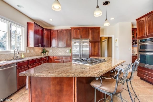 kitchen featuring hanging light fixtures, a center island, stainless steel appliances, and sink