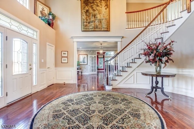 entrance foyer with wood-type flooring, crown molding, and a high ceiling