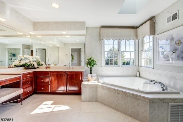 bathroom featuring tiled tub, tile patterned flooring, and vanity