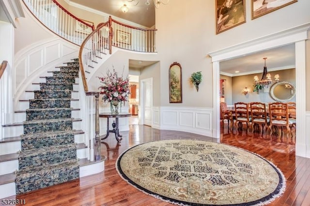 entrance foyer with a chandelier, crown molding, a towering ceiling, and wood-type flooring