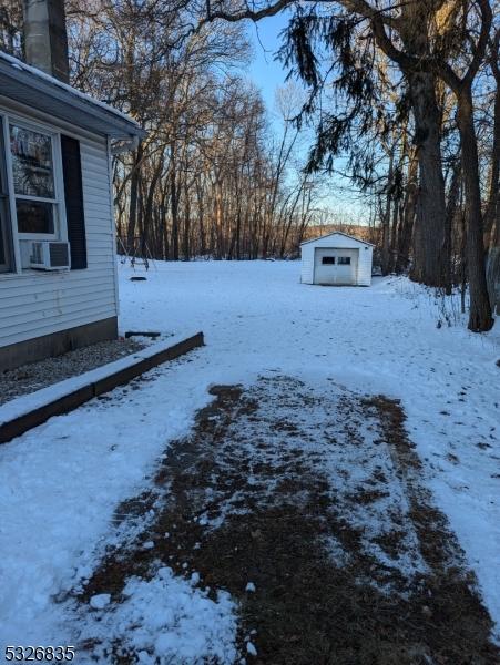 snowy yard featuring cooling unit and a storage unit