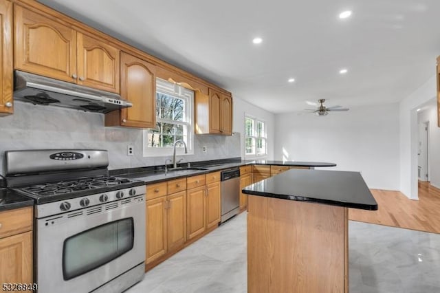 kitchen featuring appliances with stainless steel finishes, backsplash, ceiling fan, sink, and a center island