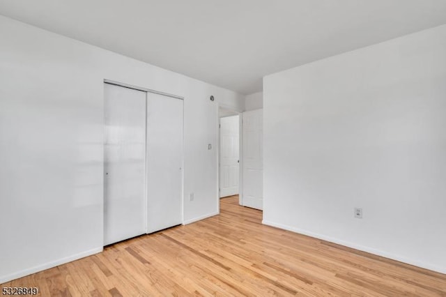 unfurnished bedroom with light wood-type flooring and a closet