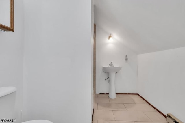 bathroom featuring tile patterned floors, sink, vaulted ceiling, toilet, and baseboard heating