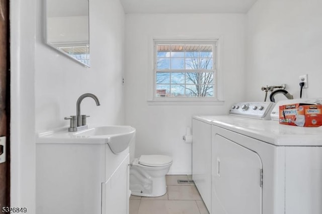 laundry room featuring light tile patterned floors, separate washer and dryer, and sink