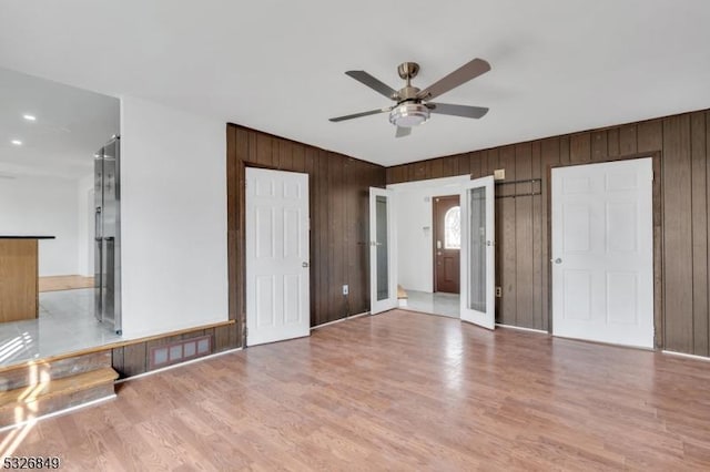 unfurnished bedroom featuring light hardwood / wood-style flooring, ensuite bath, and wooden walls