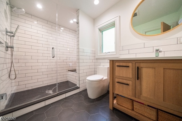 bathroom featuring vanity, tile patterned flooring, toilet, tile walls, and an enclosed shower