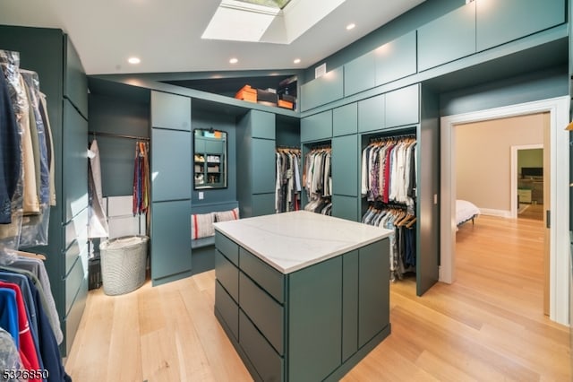 walk in closet with light wood-type flooring and vaulted ceiling