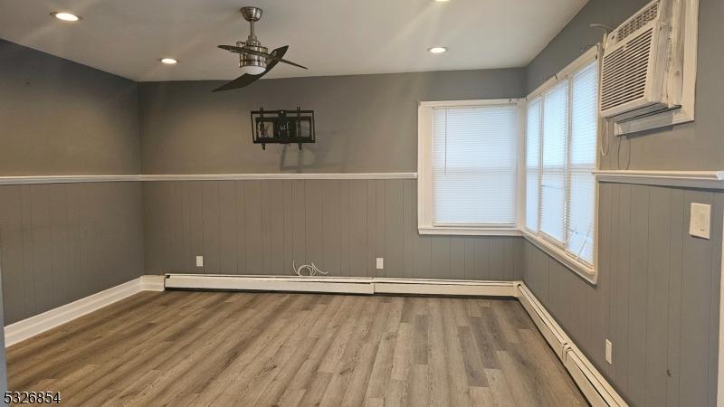 unfurnished dining area with ceiling fan, wood-type flooring, and wooden walls