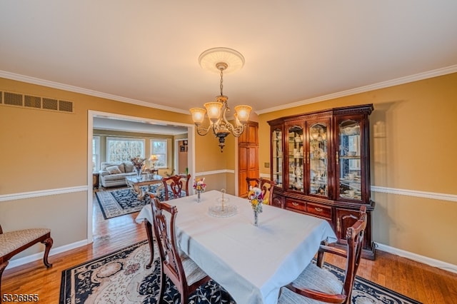 dining room featuring hardwood / wood-style flooring, an inviting chandelier, and ornamental molding