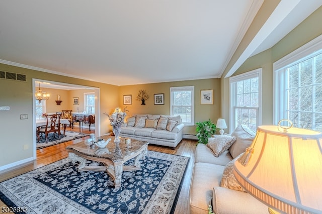 living room with baseboard heating, crown molding, light hardwood / wood-style floors, and an inviting chandelier