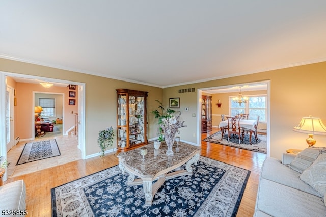 living room with light hardwood / wood-style floors, ornamental molding, and a notable chandelier