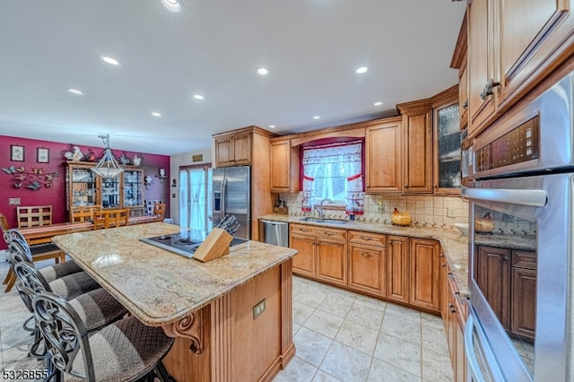 kitchen with backsplash, pendant lighting, a kitchen bar, a kitchen island, and appliances with stainless steel finishes