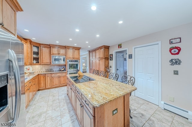 kitchen with appliances with stainless steel finishes, backsplash, a baseboard radiator, a center island, and a breakfast bar area