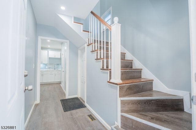 stairs with hardwood / wood-style floors and sink