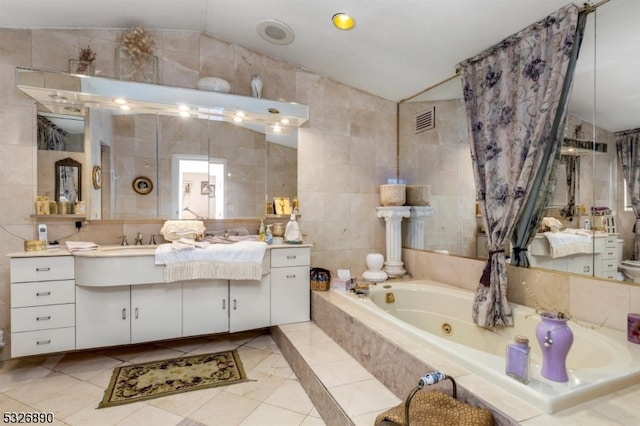 bathroom featuring vanity, lofted ceiling, a relaxing tiled tub, and tile walls