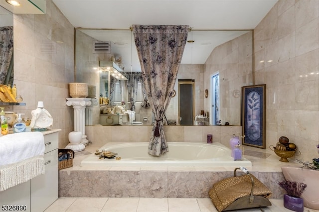 bathroom with tile patterned floors, vanity, vaulted ceiling, tile walls, and tiled bath