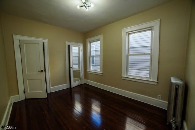 unfurnished bedroom featuring radiator and dark wood-type flooring