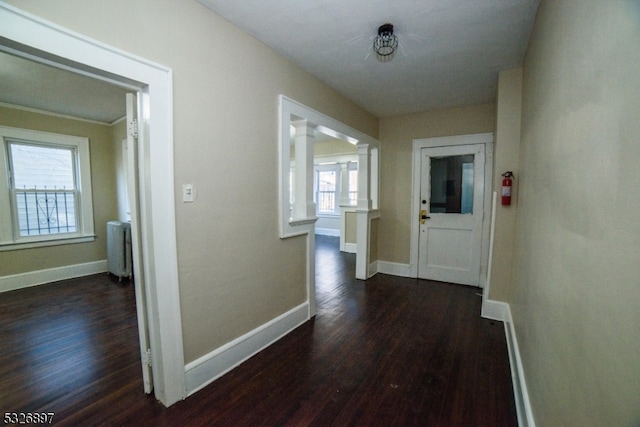 hallway with dark hardwood / wood-style floors, radiator heating unit, and decorative columns