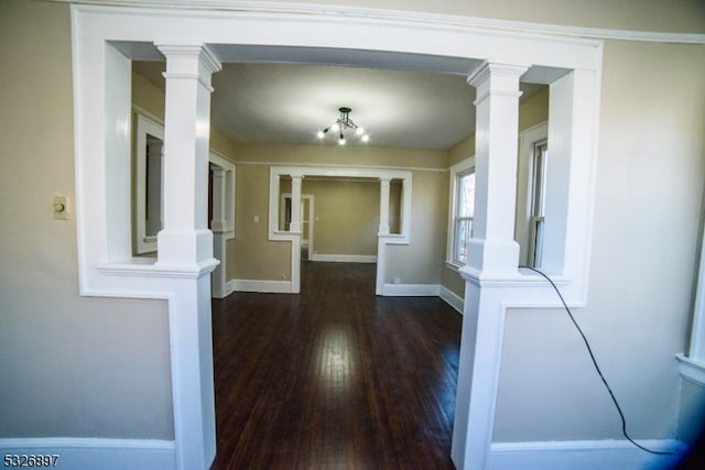 corridor featuring a chandelier, ornamental molding, and dark wood-type flooring