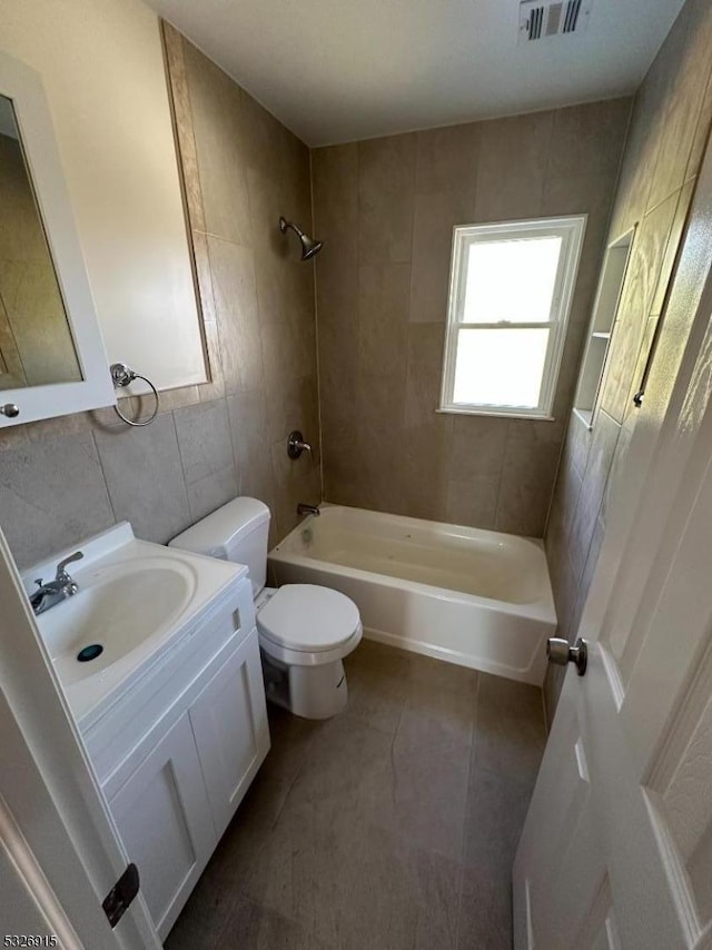 full bathroom featuring tile patterned floors, vanity, tile walls, toilet, and tiled shower / bath