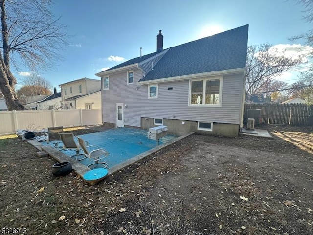 rear view of house featuring a pool and cooling unit