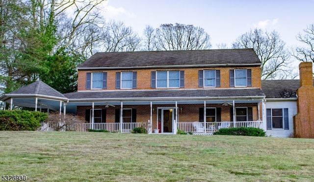 colonial house featuring covered porch and a front yard