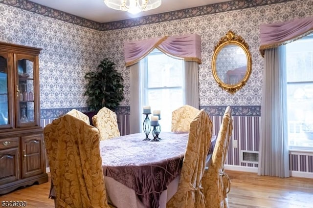 dining room with a notable chandelier, a wealth of natural light, and light hardwood / wood-style flooring