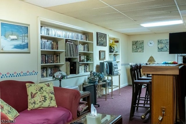 living area with carpet, built in shelves, and a paneled ceiling