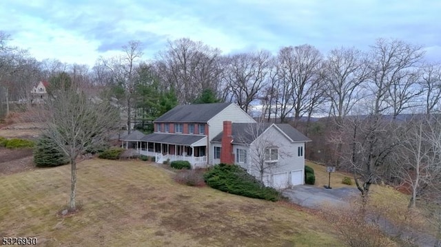 view of front facade with covered porch, a garage, and a front lawn