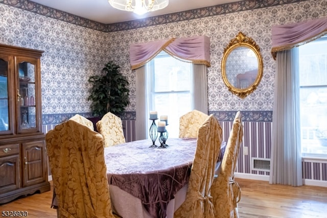 dining space with a notable chandelier, plenty of natural light, and light hardwood / wood-style flooring