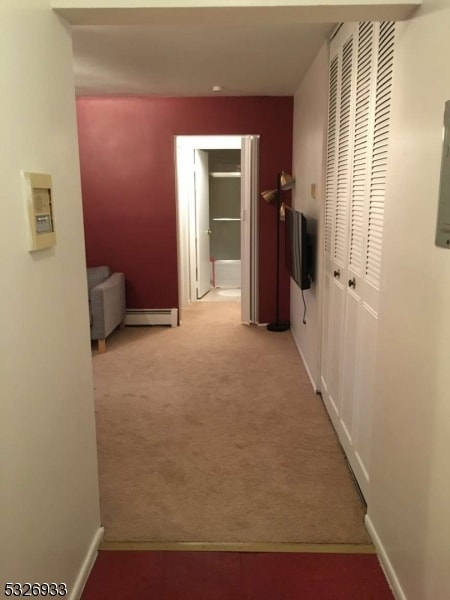 hallway with light carpet and a baseboard radiator