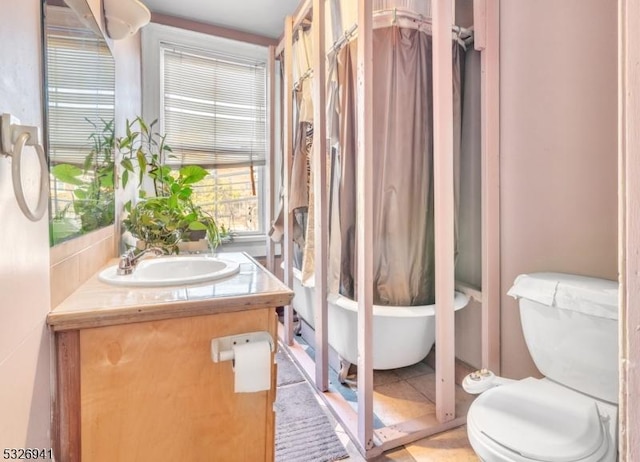 bathroom featuring tile patterned flooring, a bathtub, toilet, and vanity