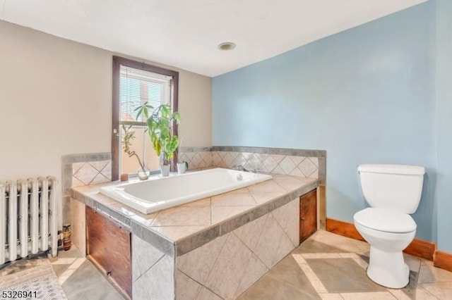 bathroom featuring tile patterned floors, tiled bath, radiator heating unit, and toilet