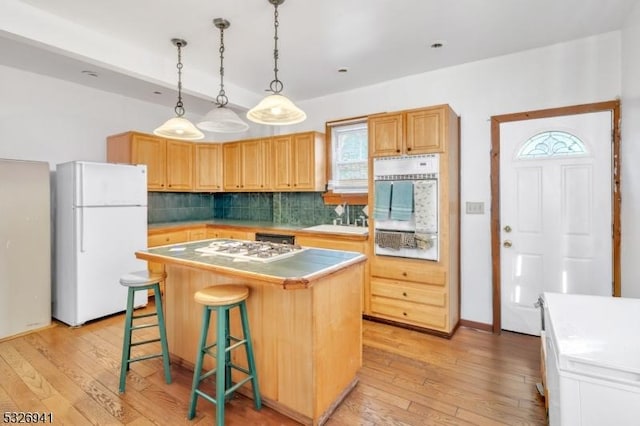 kitchen featuring backsplash, a kitchen island, white appliances, and light wood-type flooring